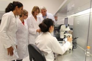 BioConsortia 研发团队的成员在显微镜下看到了最新的微生物发现。